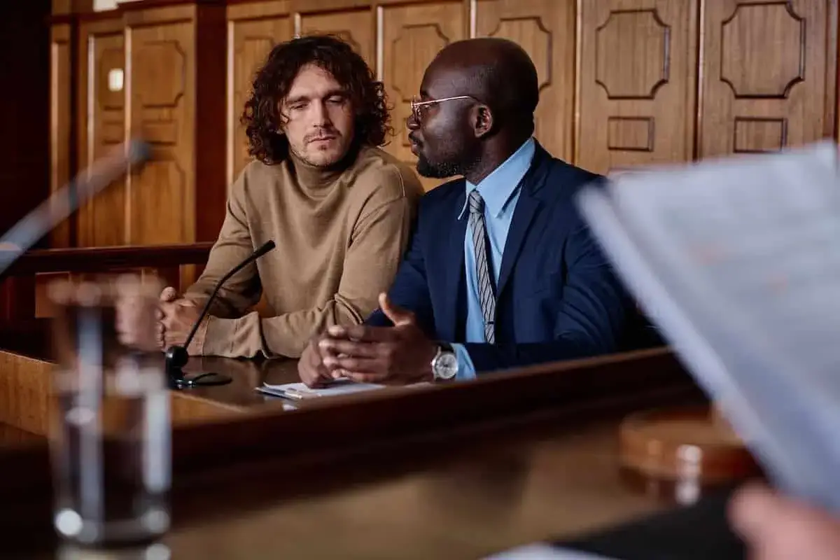 Un avocat postulant discute avec son client dans une salle d'audience.