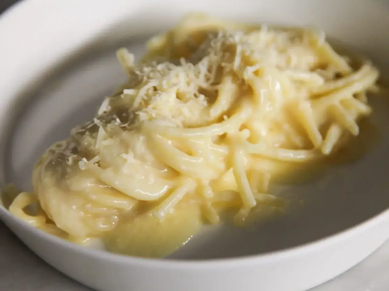 Un piatto di pasta burro e parmigiano, cremoso e invitante, con una spolverata di formaggio grattugiato.