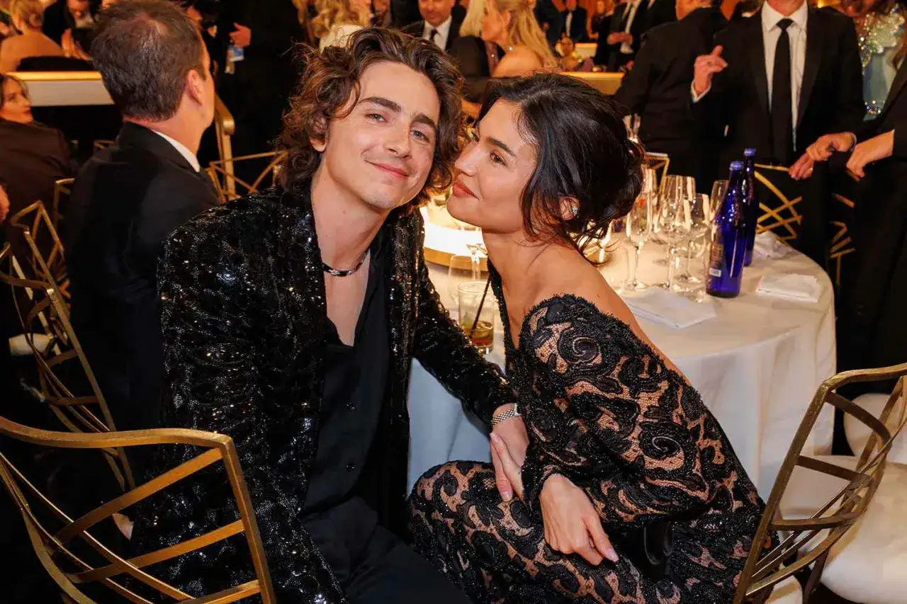 Timoth&eacute;e Chalamet och Kylie Jenner delar ett &ouml;gonblick vid ett bord, omgivna av andra g&auml;ster.