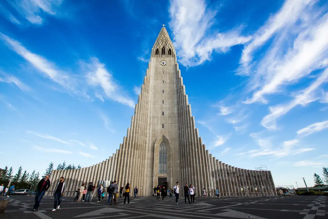 Charakterystyczny kościół Hallgrímskirkja w **Reykjaviku** pod błękitnym niebem z chmurami.