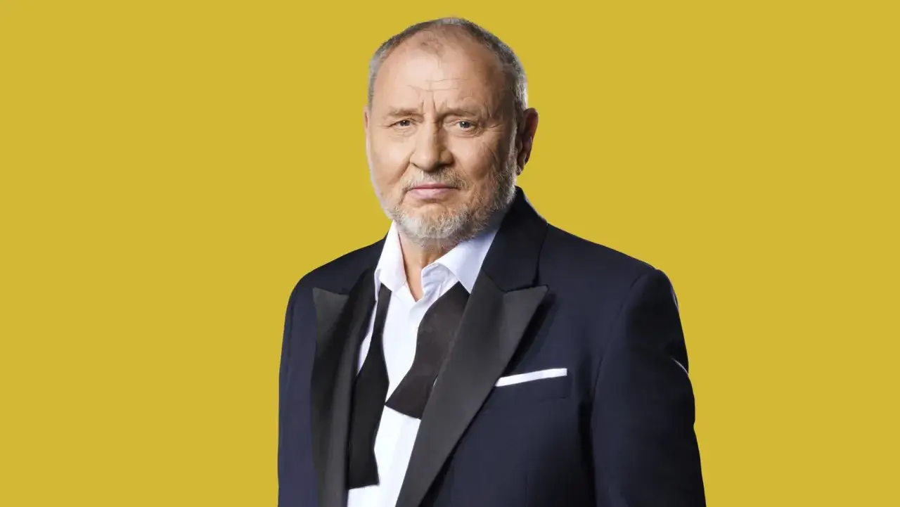 Andrzej Grabowski żyje i wygląda świetnie w czarnym smokingu na żółtym tle.