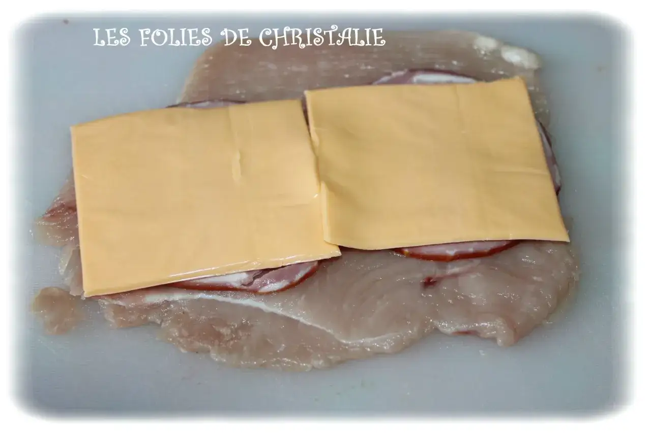 Préparation d'un cordon bleu : escalope de poulet garnie de jambon et de fromage fondu.