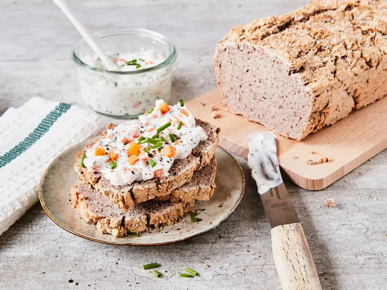 Herzhaftes Brot aus Buchweizen-Getreide, belegt mit cremigem Aufstrich und frischen Kr&auml;utern. Dazu ein Laib Brot und ein Glas Dip.
