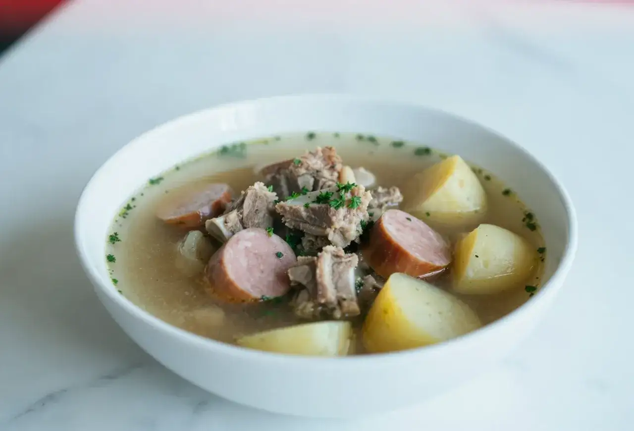 Aromatyczna zupa na żeberkach z kawałkami kiełbasy i ziemniaków, posypana natką pietruszki.