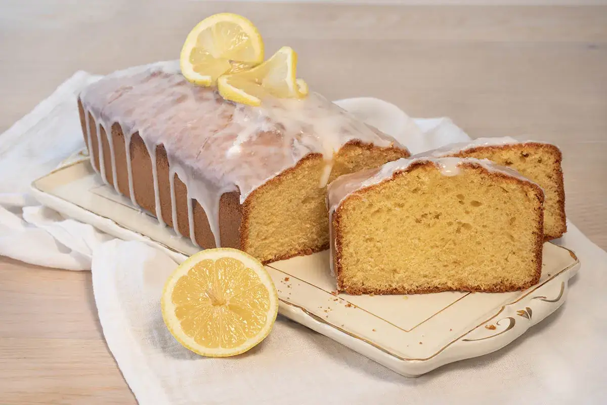 Un delicioso bizcocho de limón cubierto con glaseado blanco y decorado con rodajas de limón.