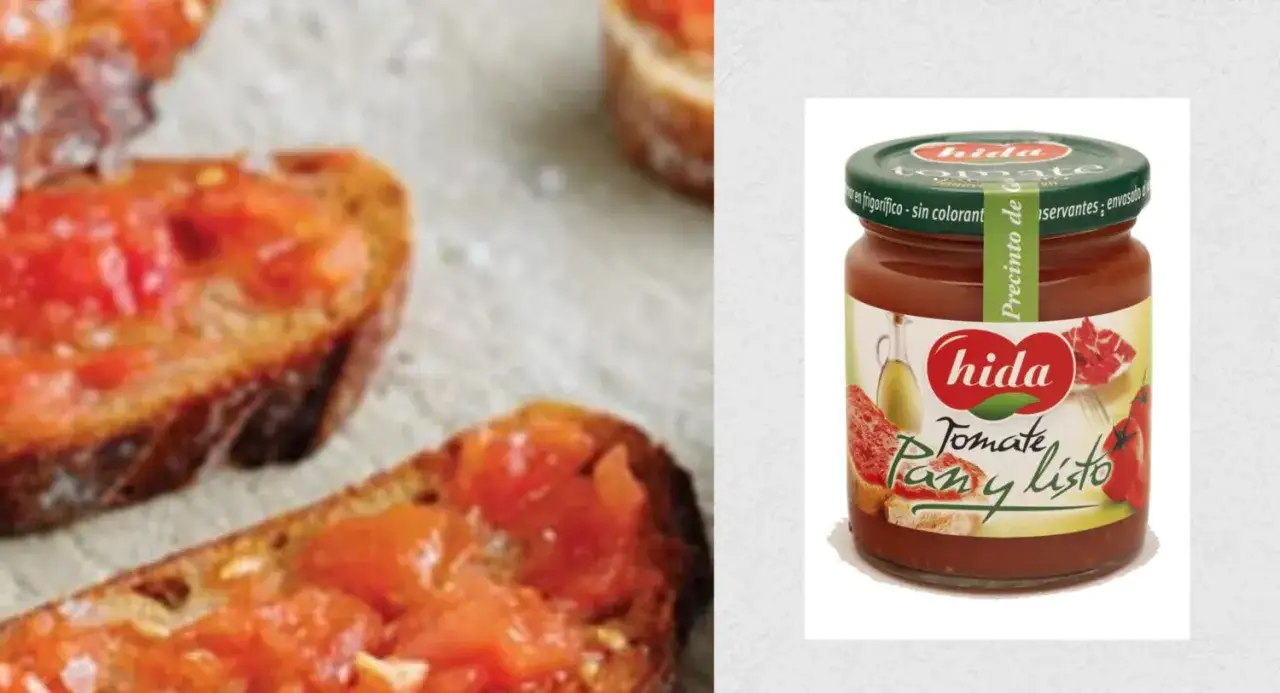Tostadas con tomate rallado y un tarro de Hida Tomate Pan y Listo. El **oli verd** de la etiqueta evoca frescura.