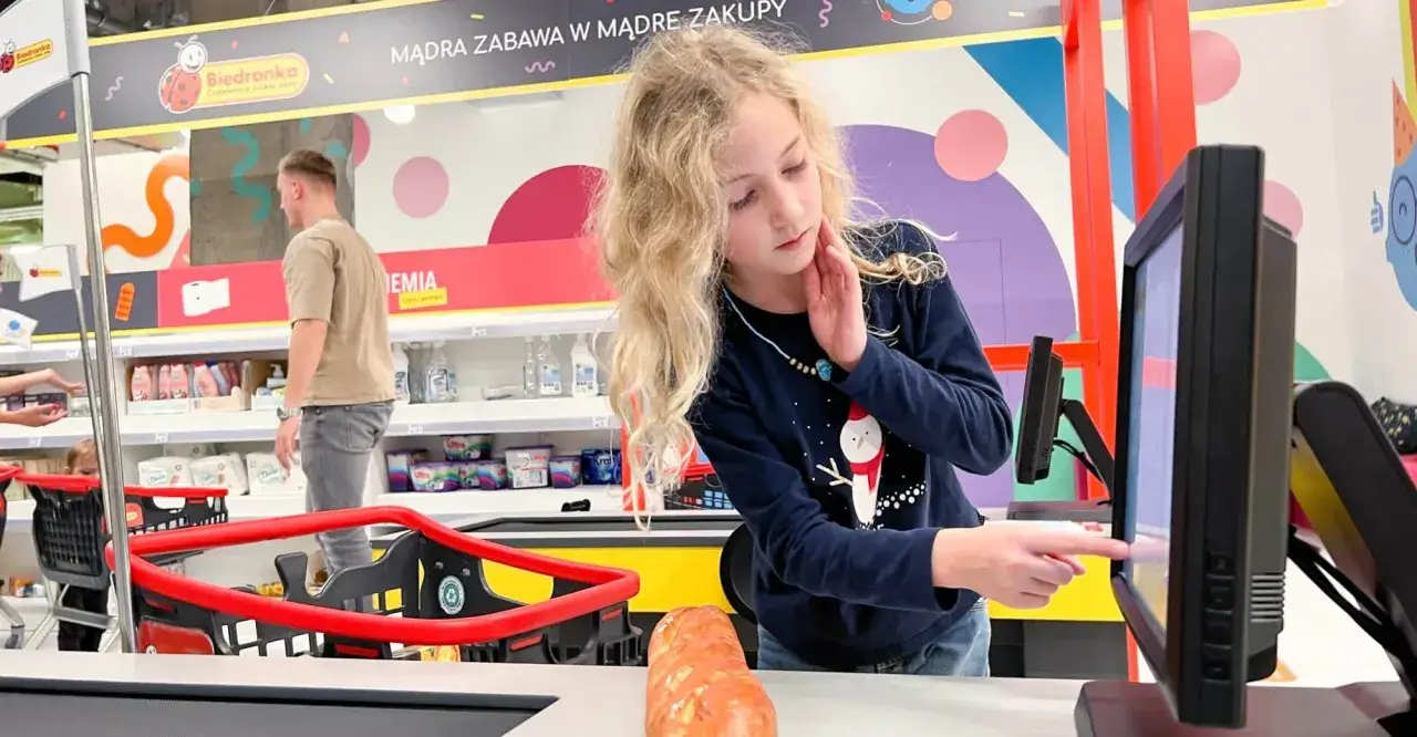 Dziewczynka bawi się kasą w sklepie Biedronka w Warszawie, ucząc się mądrych zakupów.