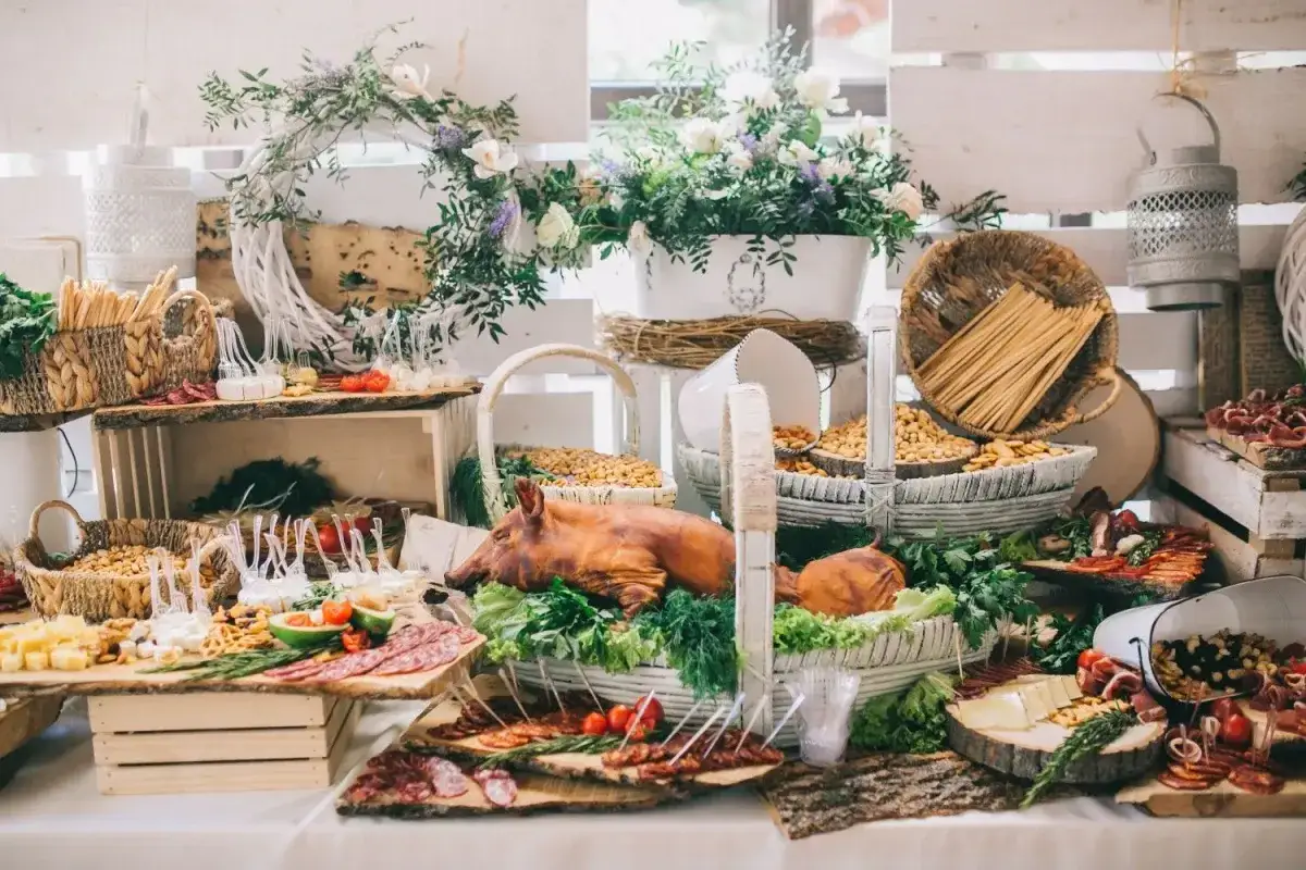 Uroczyste menu na wesele w domu: pieczony prosiak, sery, wędliny, orzechy i świeże kwiaty tworzą bogaty stół.
