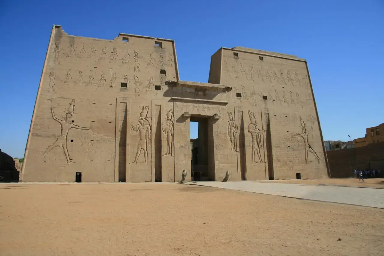 Imponente templo de la civilización de Egipto, con jeroglíficos y figuras talladas en sus muros de piedra bajo un cielo azul.
