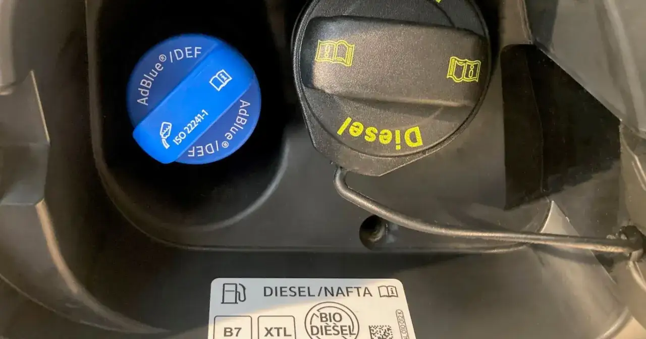 Korek AdBlue i korek paliwa Diesel w samochodzie 3.0 TDI. Obok symbol instrukcji obsługi.