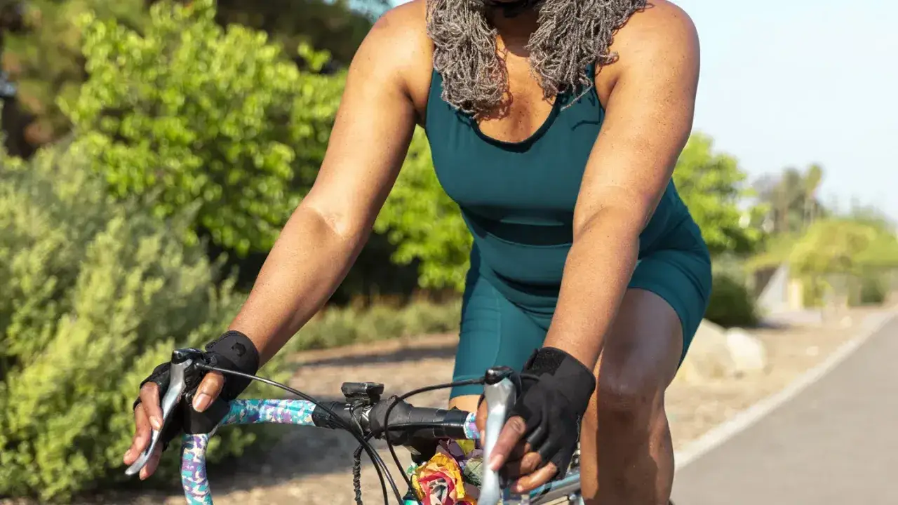 Kobieta w sportowym stroju jedzie na rowerze, odkrywając jak jeździć na rowerze żeby schudnąć.