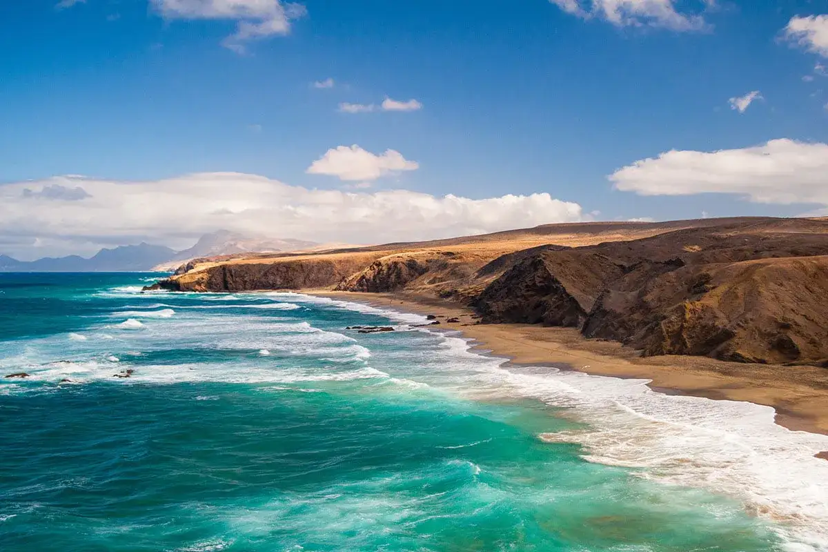 Fuerteventura w marcu: słoneczna pogoda, turkusowe morze i piaszczysta plaża z klifami. Idealne warunki do wypoczynku.