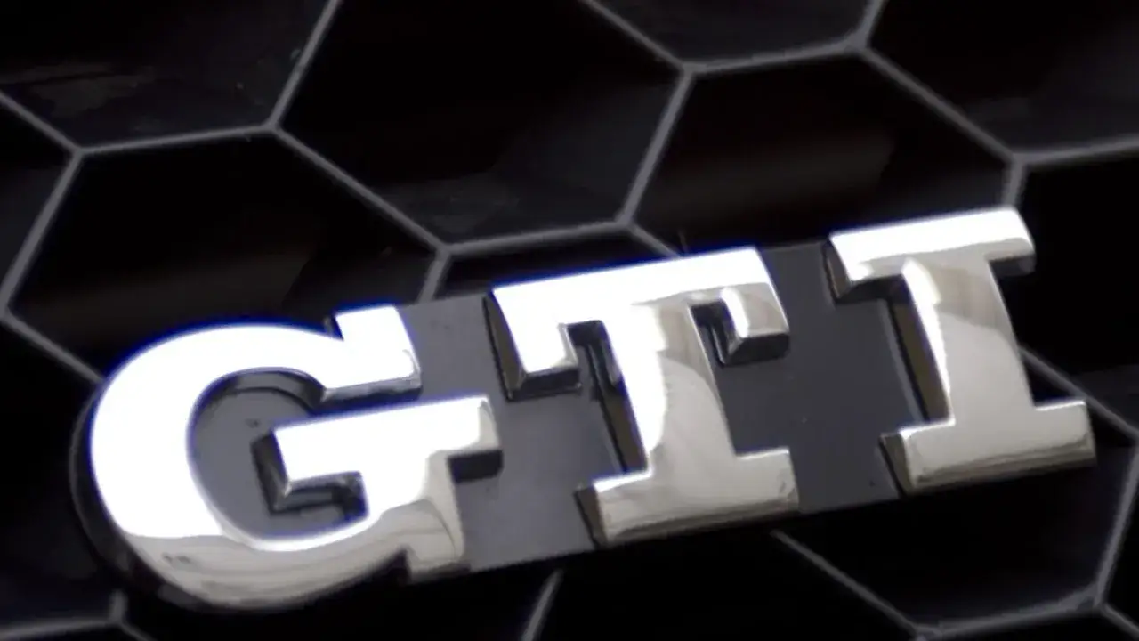 Emblema cromado con las siglas GTI sobre una parrilla negra de dise&ntilde;o hexagonal.