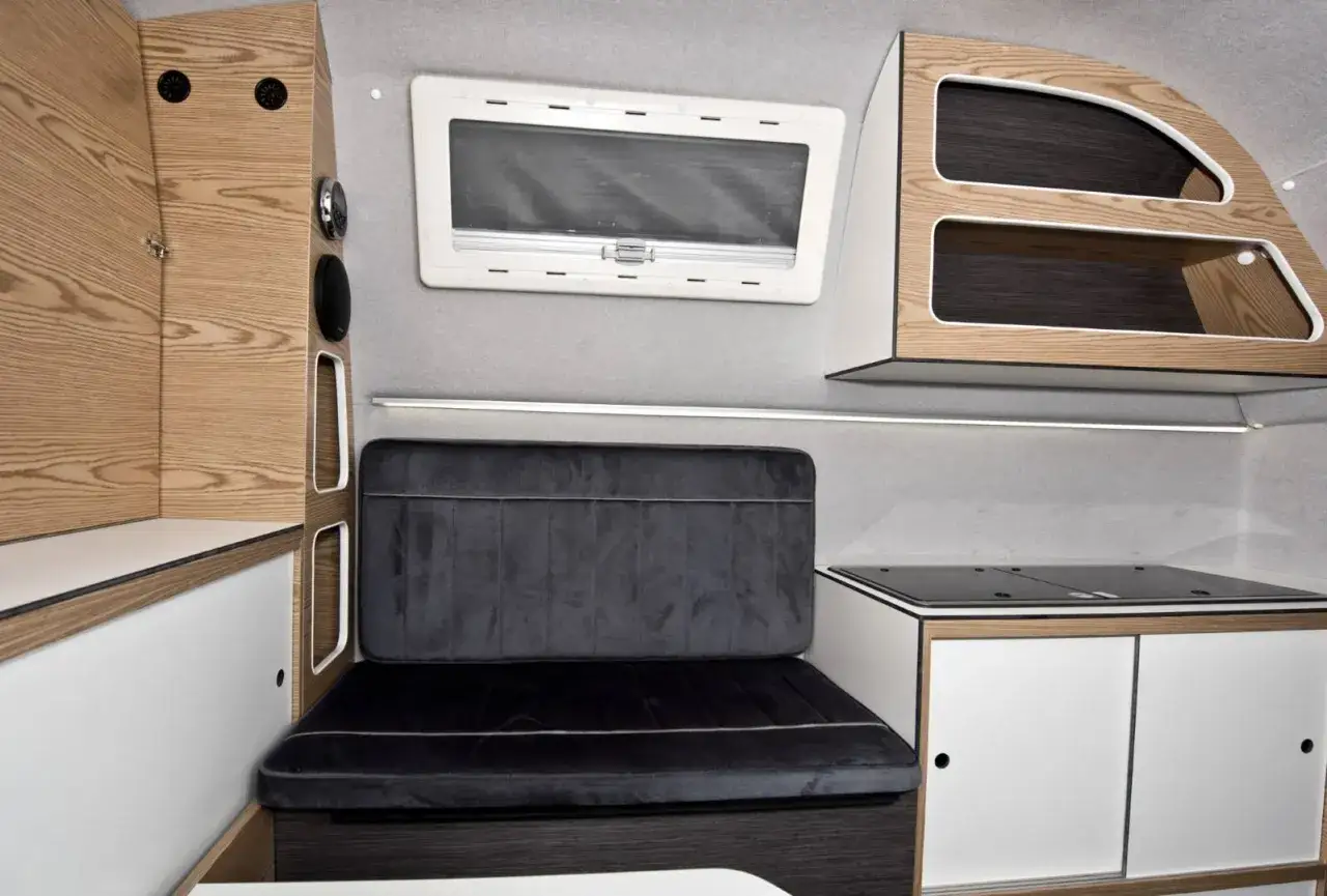 Wnętrze kampera Mitsubishi z wygodną kanapą, aneksem kuchennym i schowkami. Idealne na podróże.