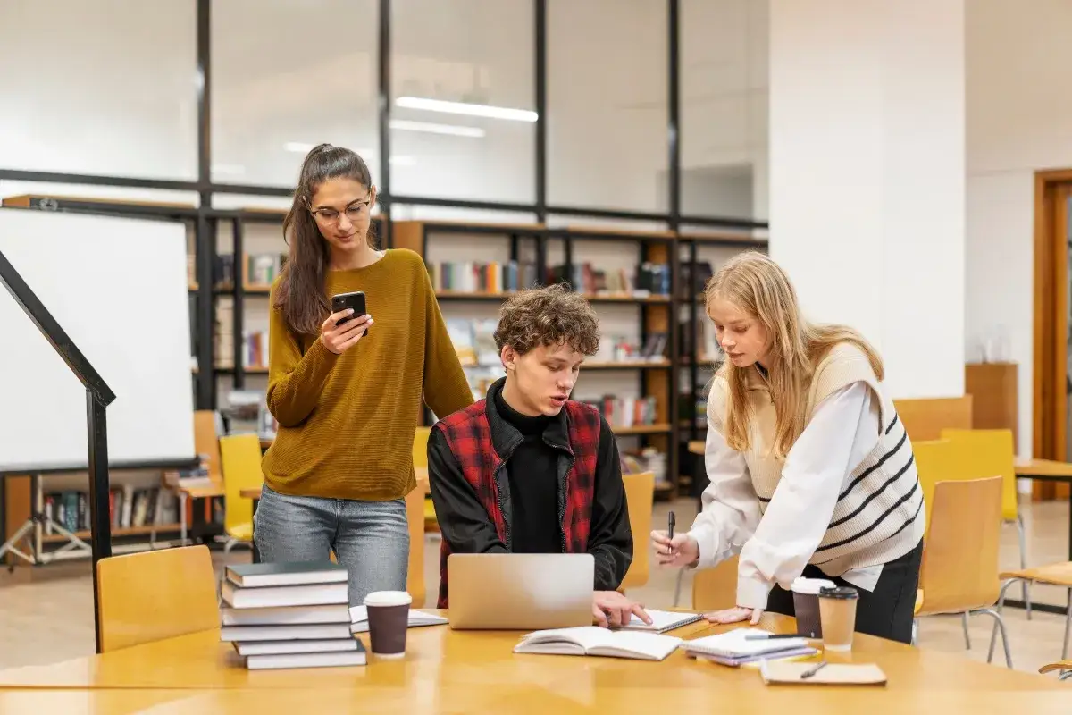 Students discuss their studies, comparing the merits of masters in organizational leadership vs MBA programs while working on a project in a library.