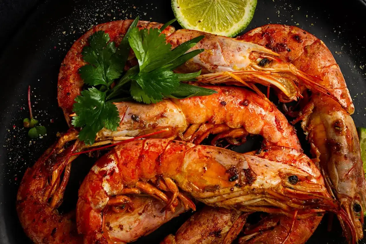 Gambones a la plancha, jugosos y dorados, servidos con perejil fresco y rodajas de lima.