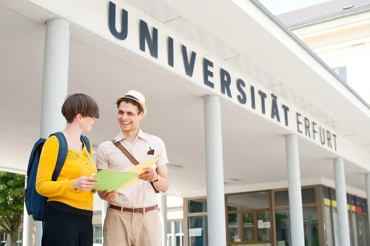 Zwei junge Leute planen ihr Studium in Erfurt und schauen auf eine Karte vor dem Universit&auml;tsgeb&auml;ude.