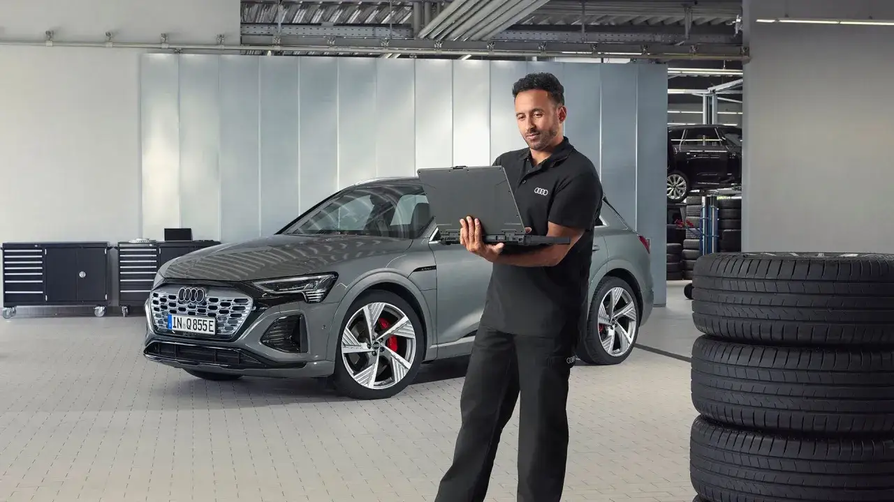 T&eacute;cnico revisa un Audi el&eacute;ctrico con port&aacute;til. El mantenimiento de tu Audi es esencial para su rendimiento.