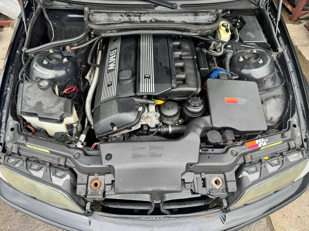 Silnik BMW E46 lift. Widoczny jest silnik z osprzętem, w tym pokrywa zawor&oacute;w z napisem BMW, zbiornik płynu chłodniczego i elementy układu dolotowego.