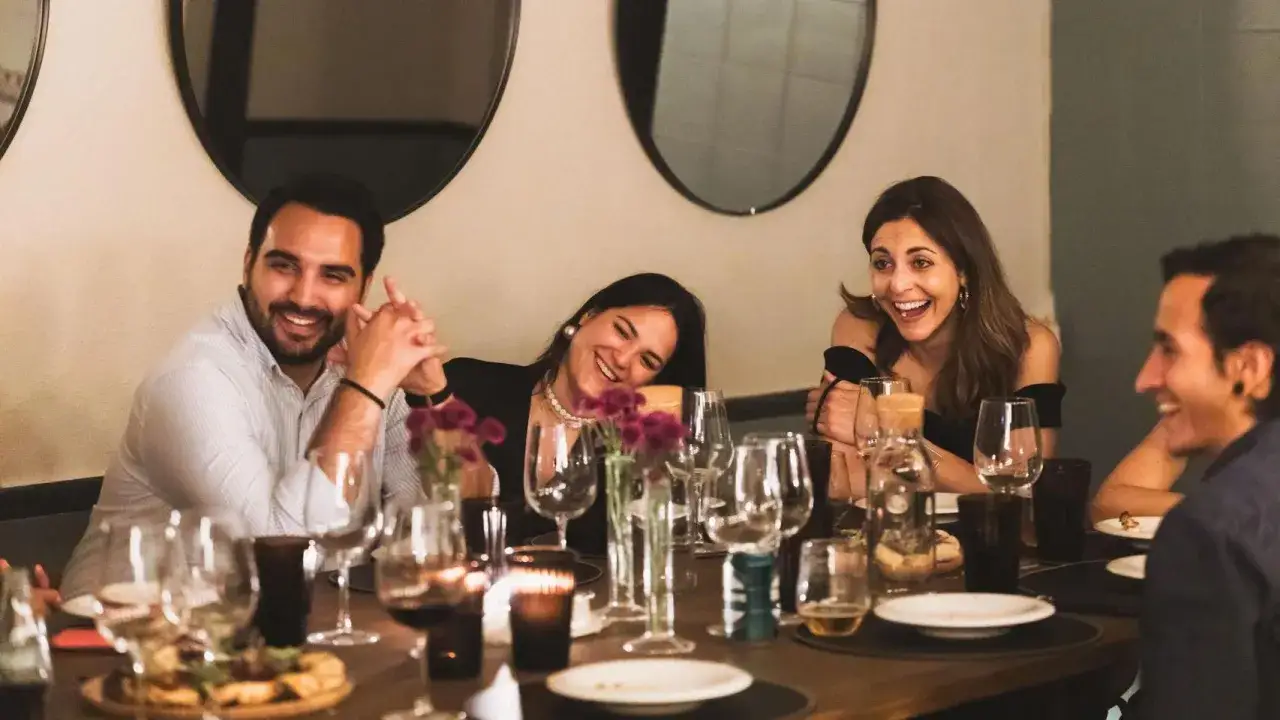 Amigos riendo en una cena. Las **timeleft opiniones** sobre este restaurante son muy positivas, ¡se nota la alegría!