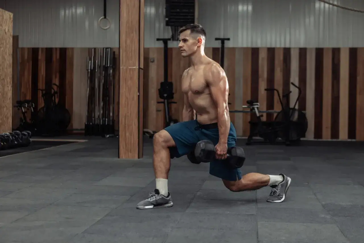 Man utf&ouml;r utfallssteg med vikt i ett gym.