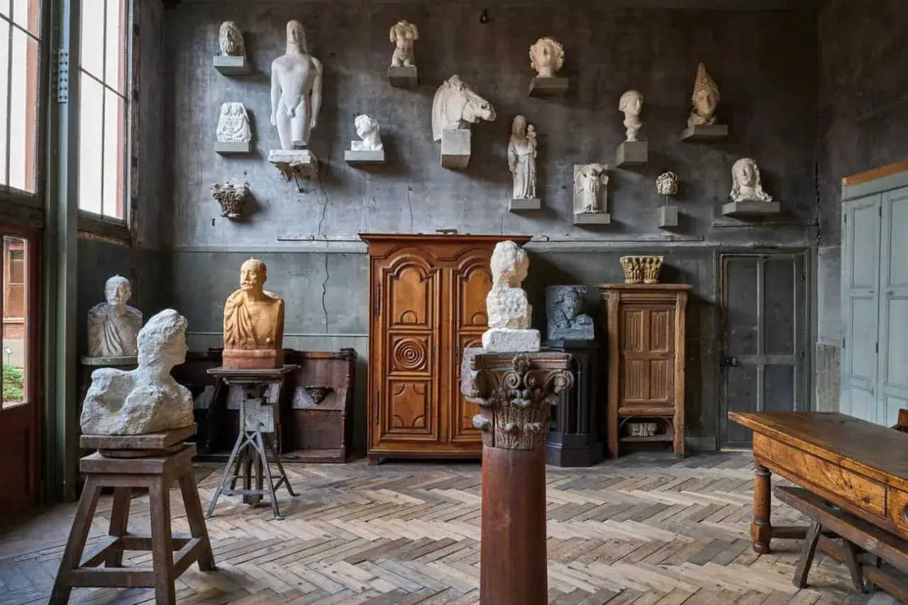 Atelier d'une micro entreprise artiste auteur, rempli de bustes et sculptures classiques sur des &eacute;tag&egrave;res et socles.
