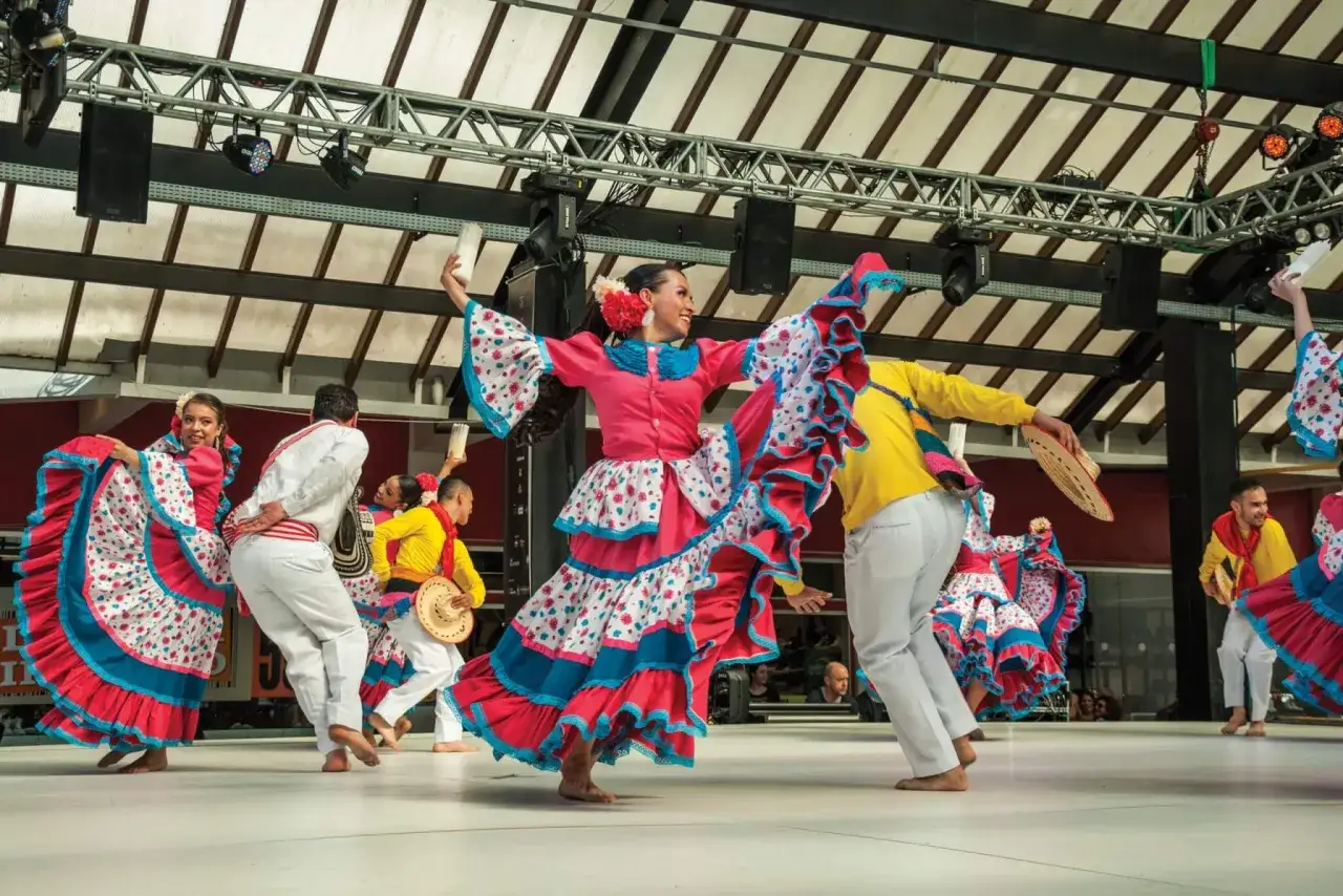 Danzatori in abiti colorati eseguono diversi tipi di balli tradizionali, con gonne ampie e vivaci che volteggiano.