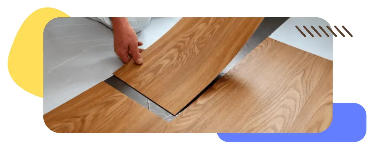 Instalaci&oacute;n de suelo laminado SPC con acabado de madera. Una mano coloca una tabla sobre otra, mostrando el sistema de uni&oacute;n.