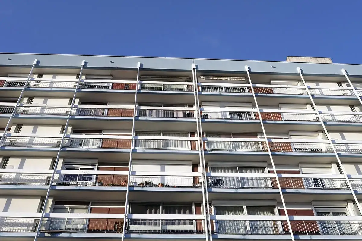 Façade d'immeuble avec balcons, prêt pour un bail à réhabilitation. Le ciel bleu domine.