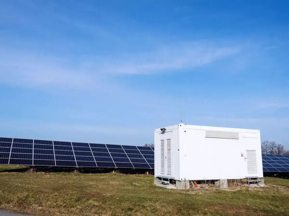 Biały kontener magazynu energii 50 kWh na tle paneli słonecznych. Sprawdź aktualną cenę!