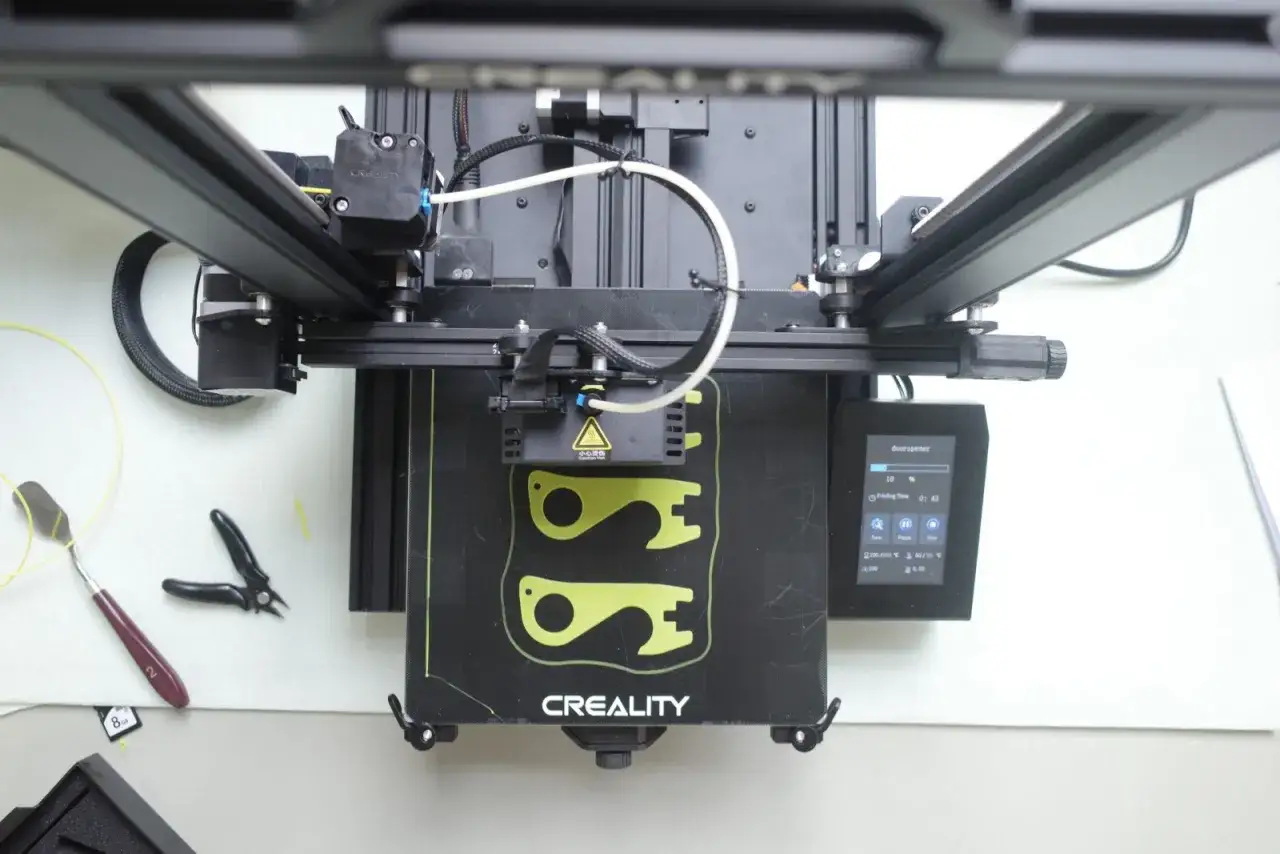 Drukarka 3D Creality w trakcie pracy, obok narzędzia do serwisowania drukarek 3D.