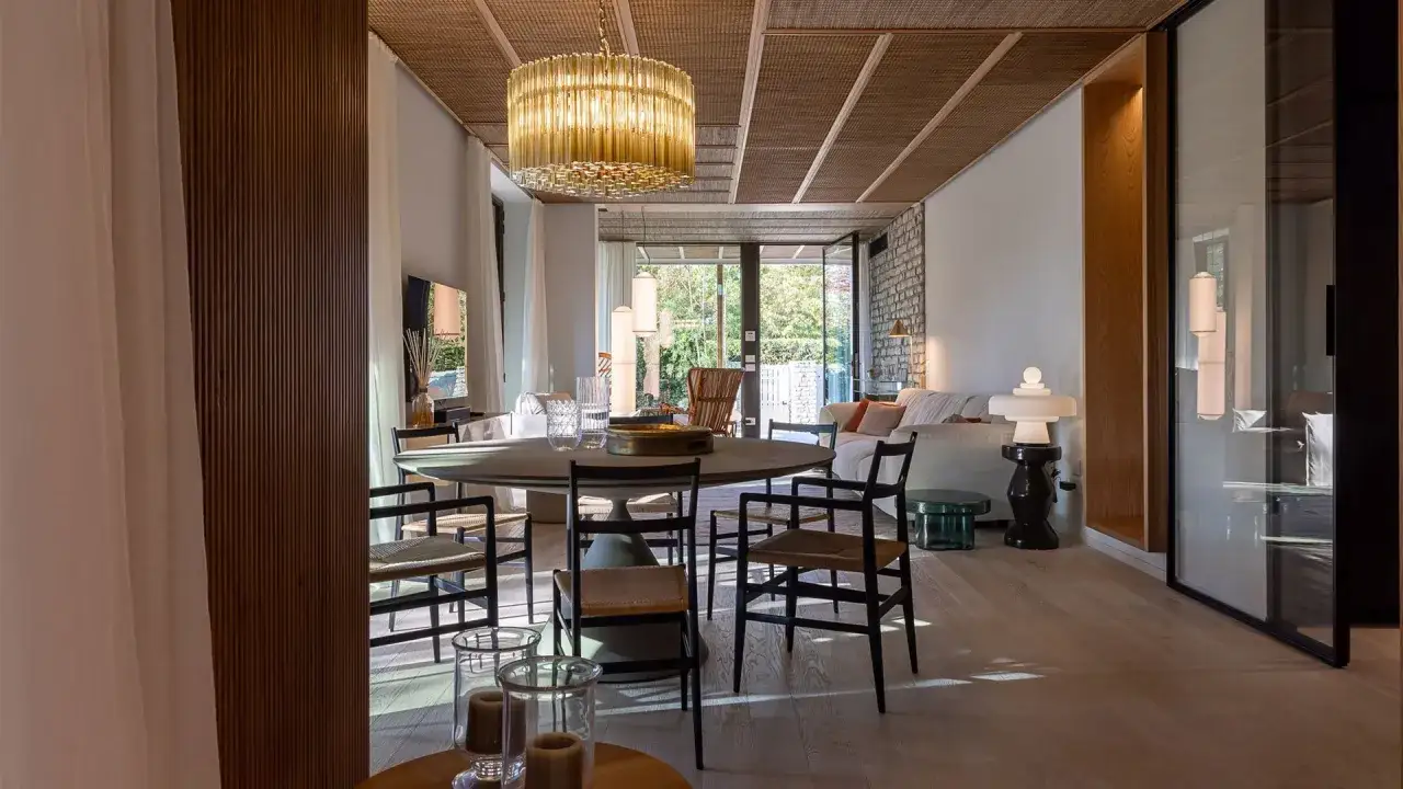 Interni luminosi con arredi moderni, un grande tavolo rotondo e un lampadario scenografico. Case eleganti e raffinate che invitano al relax.