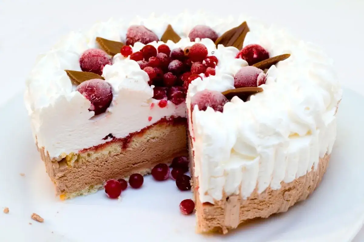 Una deliziosa torta al gelato, stratificata con pan di Spagna, gelato al cioccolato, confettura di frutti rossi e panna montata, decorata con frutti di bosco e cioccolato.