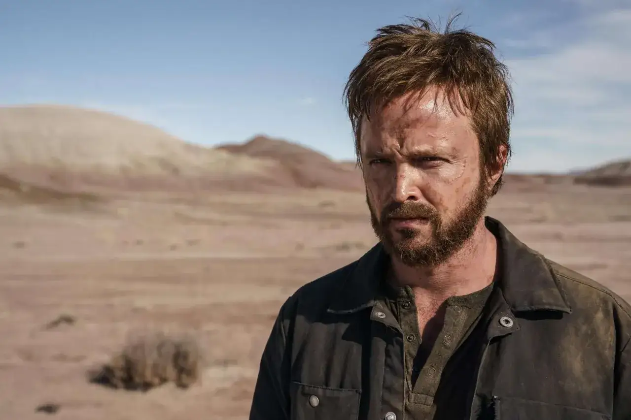 Jesse Pinkman, zmęczony i brudny, stoi na pustyni. W tle piaszczyste wzgórza i błękitne niebo.