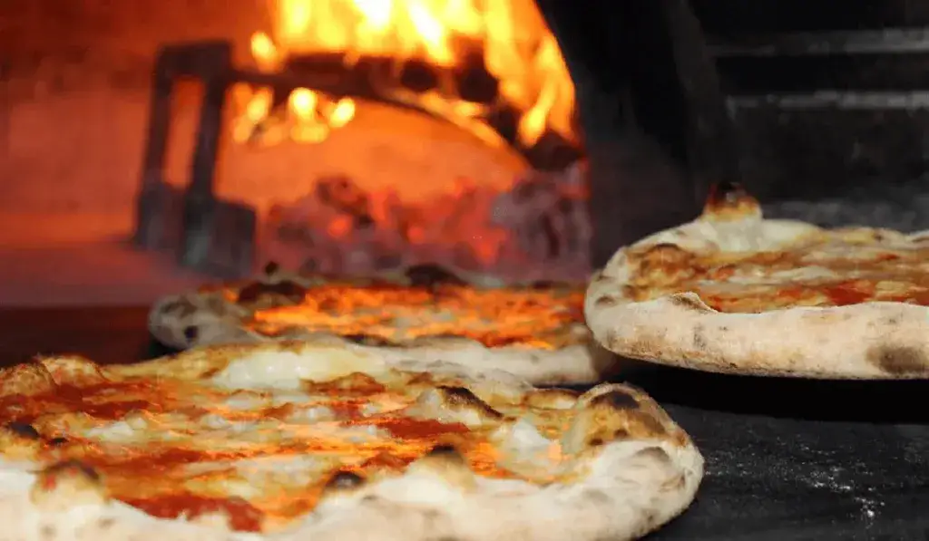 pizza artesanal saliendo de un horno de leña en un restaurante
