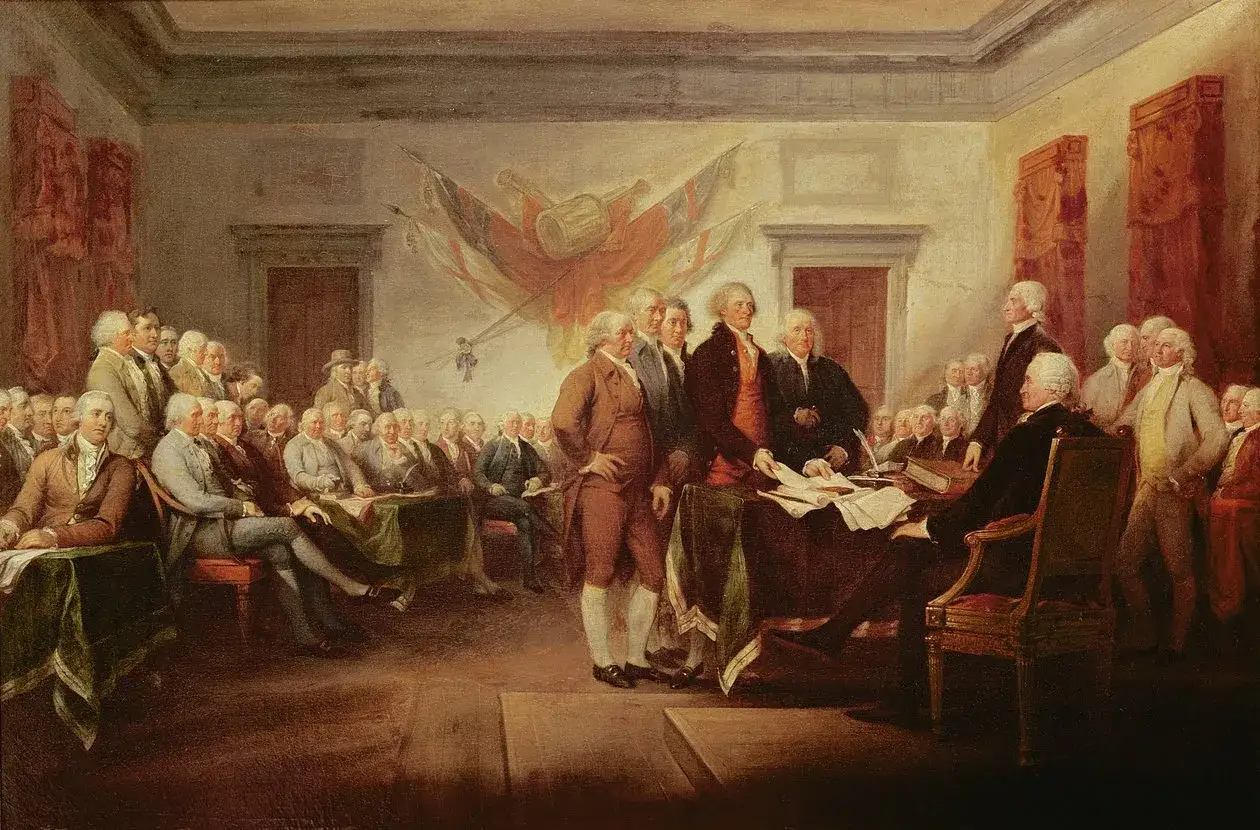 Obraz przedstawia moment podpisania **Deklaracji Niepodległości USA**. Grupa mężczyzn w strojach z XVIII wieku zbiera się wokół stołu, by podpisać ważny dokument.