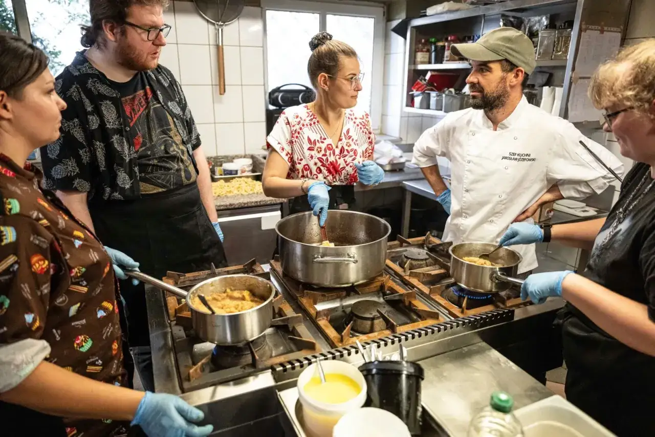 Grupa osób uczy się gotować podczas zajęć w kuchni. To świetny przykład na studia gastronomiczne Wrocław.