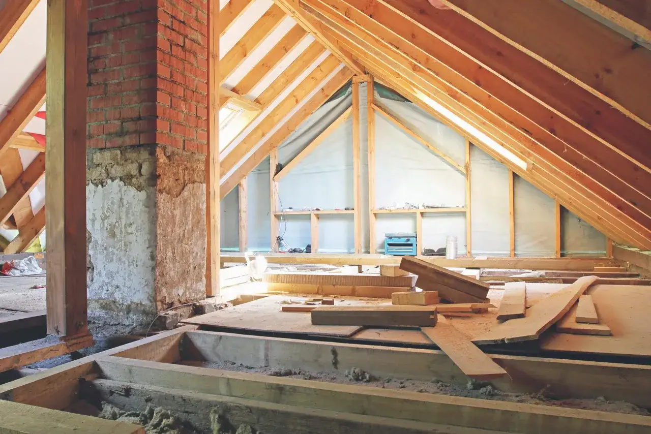 Travaux de cr&eacute;ation d'un plancher dans les combles : charpente en bois, mat&eacute;riaux de construction et chemin&eacute;e en briques.