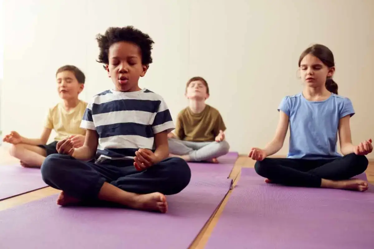 Barn sitter på yogamattor och mediterar. De har slutna ögon och lugna ansikten, som om de försöker att inte vara **arg hela tiden**.