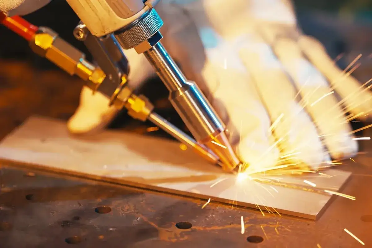 Precyzyjne spawanie laserowe aluminium, iskry sypią się podczas pracy.