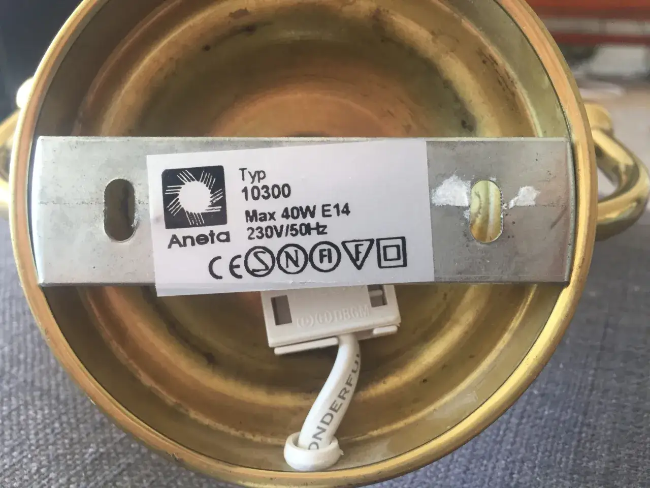 Detaljer p&aring; en ojordad lampa i m&auml;ssing. Etikett visar typ 10300, max 40W E14, 230V/50Hz.