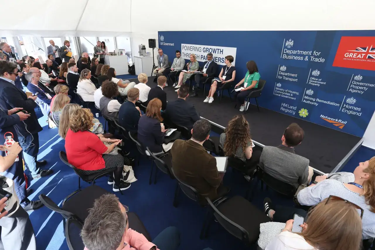 Panelists discuss the principle of authority at a UK Government event, with attendees listening attentively.