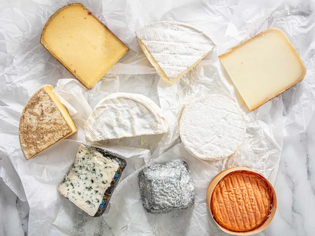 Variedad de quesos, incluyendo un trozo de queso brie. Si te preocupan las queso brie calorias, hay opciones para todos los gustos.