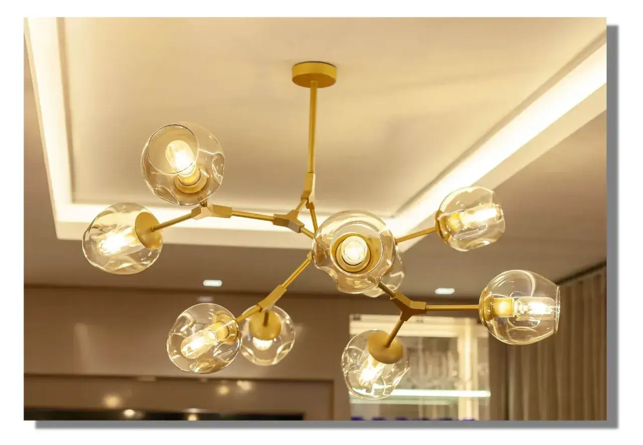 Elegante lámpara oro con esferas de cristal y luces cálidas, colgando del techo.