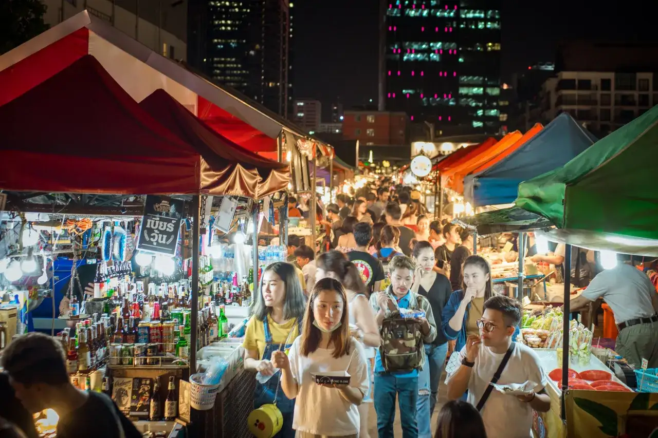 Livligt marknad i Bangkok på natten med folk som strosar bland tält och matstånd.
