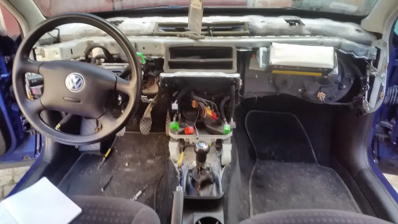 Wnętrze Golfa 4 w trakcie wymiany nagrzewnicy. Deska rozdzielcza zdemontowana, widoczne przewody i elementy mechanizmu.