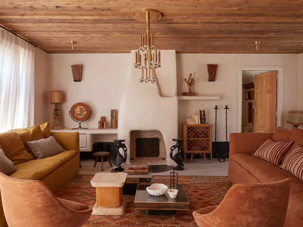 Ambiance chaleureuse dans cet interieur maison ile de ré, avec ses canapés ocre, sa cheminée blanche et son plafond en bois brut.