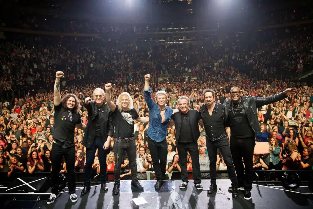 Zespół Bon Jovi na koncercie, z fanami w tle.