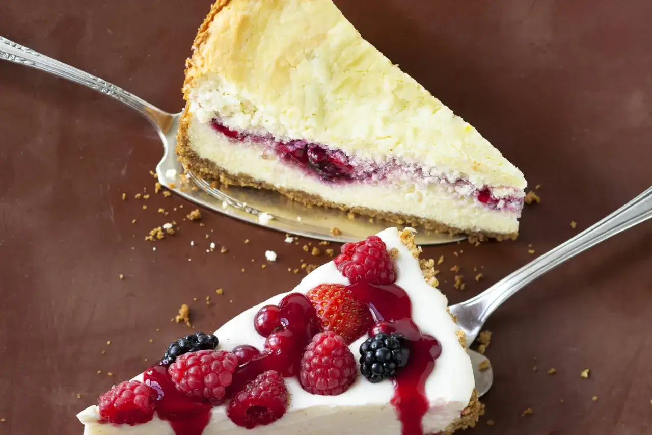 Zwei cremige Tortenst&uuml;cke, eines mit Beeren, das andere mit Kirschen, serviert auf Tortenhebern. Ein k&ouml;stlicher Kuchen ohne Backen.