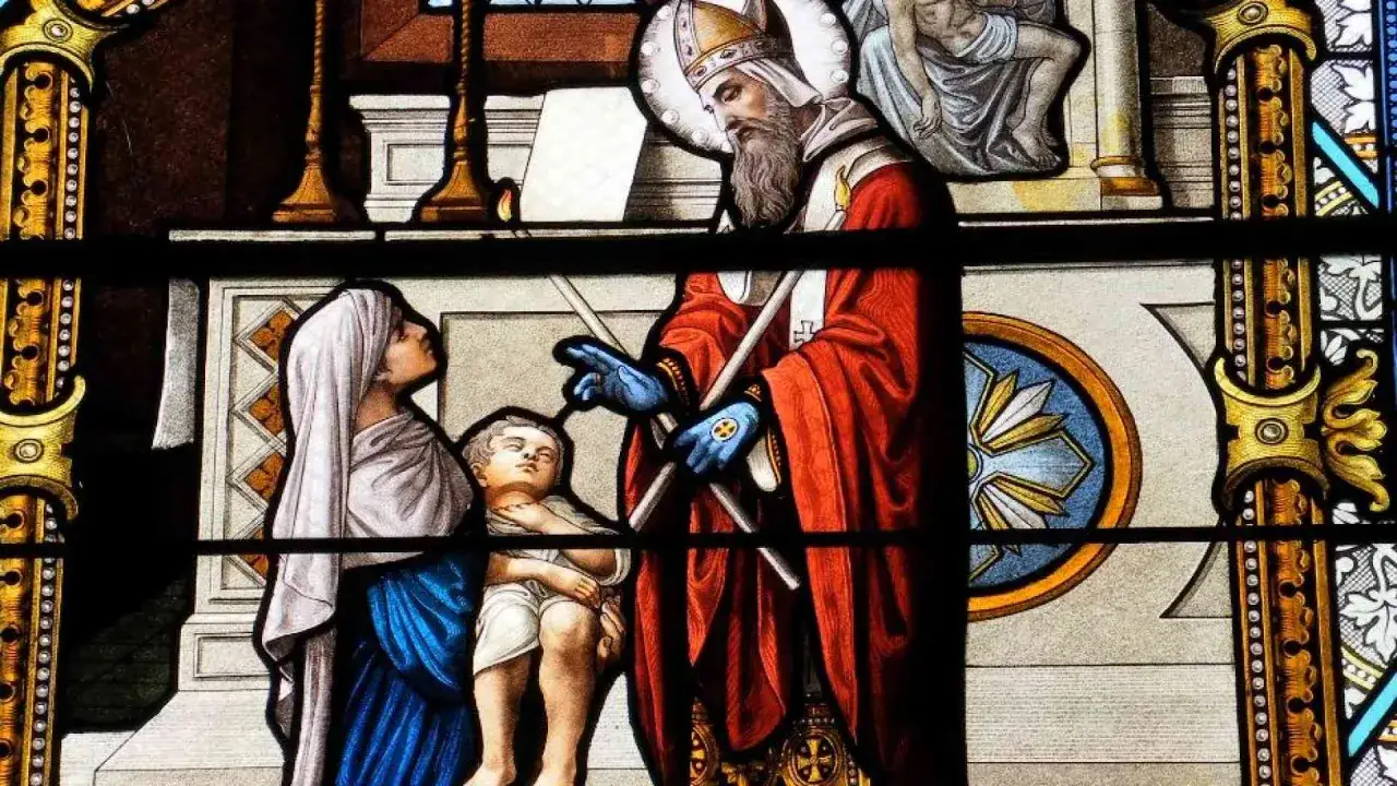 Vetrata con San Biagio che benedice un bambino, un'immagine che ricorda il proverbio